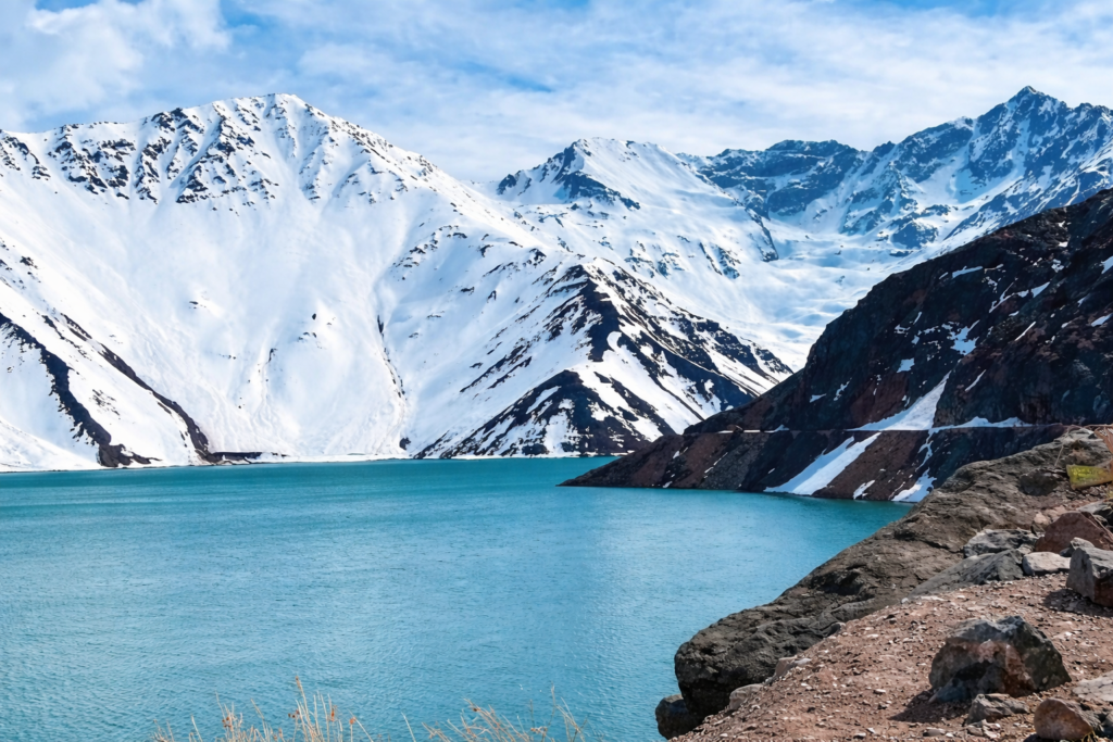 Embalse El Yeso com águas azul-turquesa e montanhas nevadas na Cordilheira dos Andes no Chile