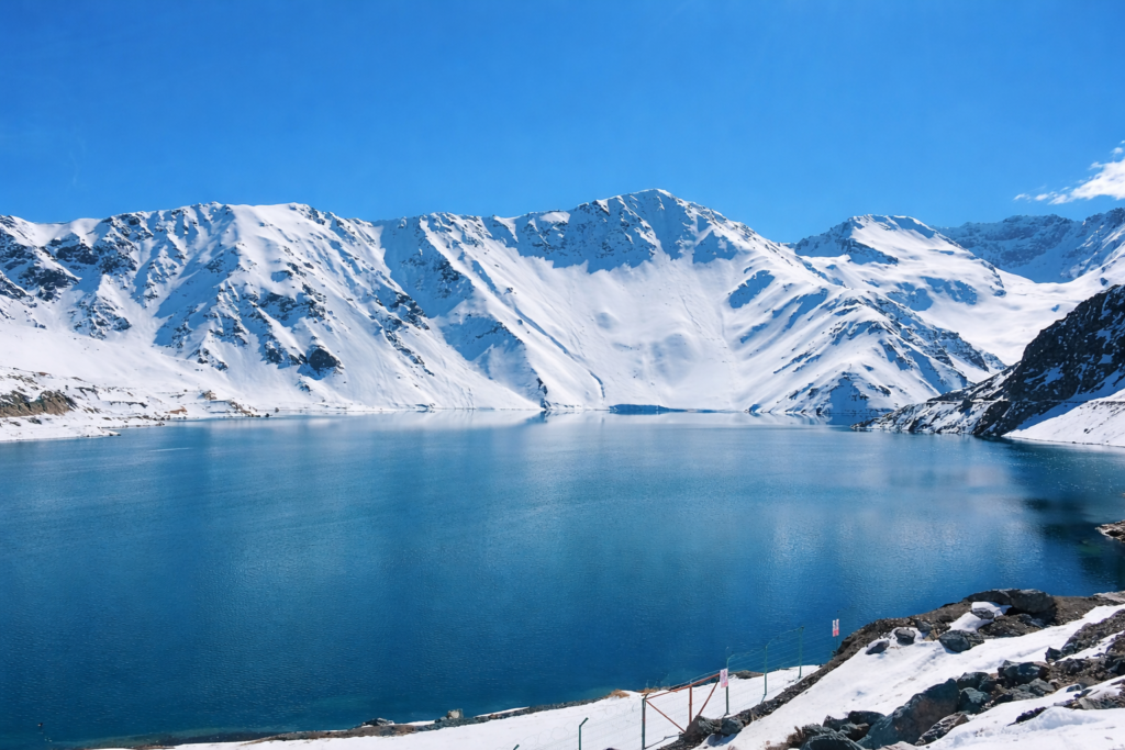 Embalse El Yeso com lago azul e montanhas nevadas da Cordilheira dos Andes no Chile